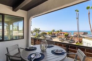 A balcony with a table set for dining, overlooking a residential area with palm trees and a view of the sea. - Rooftop w/ Hot Tub, Ocean Views | 259 Trailhead Trestles 1 by AvantStay (San Clemente)