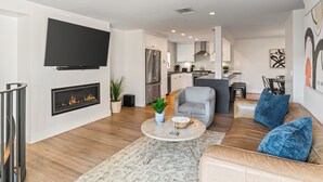 Ein modernes Wohnzimmer mit Kamin, einer Couch, einem Couchtisch und einem an der Wand montierten Fernseher.