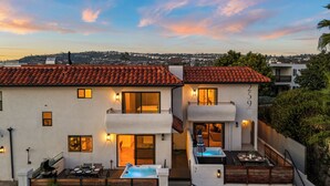 Ein zweistöckiges Haus mit Terrasse, Whirlpool und Blick auf die Stadt.