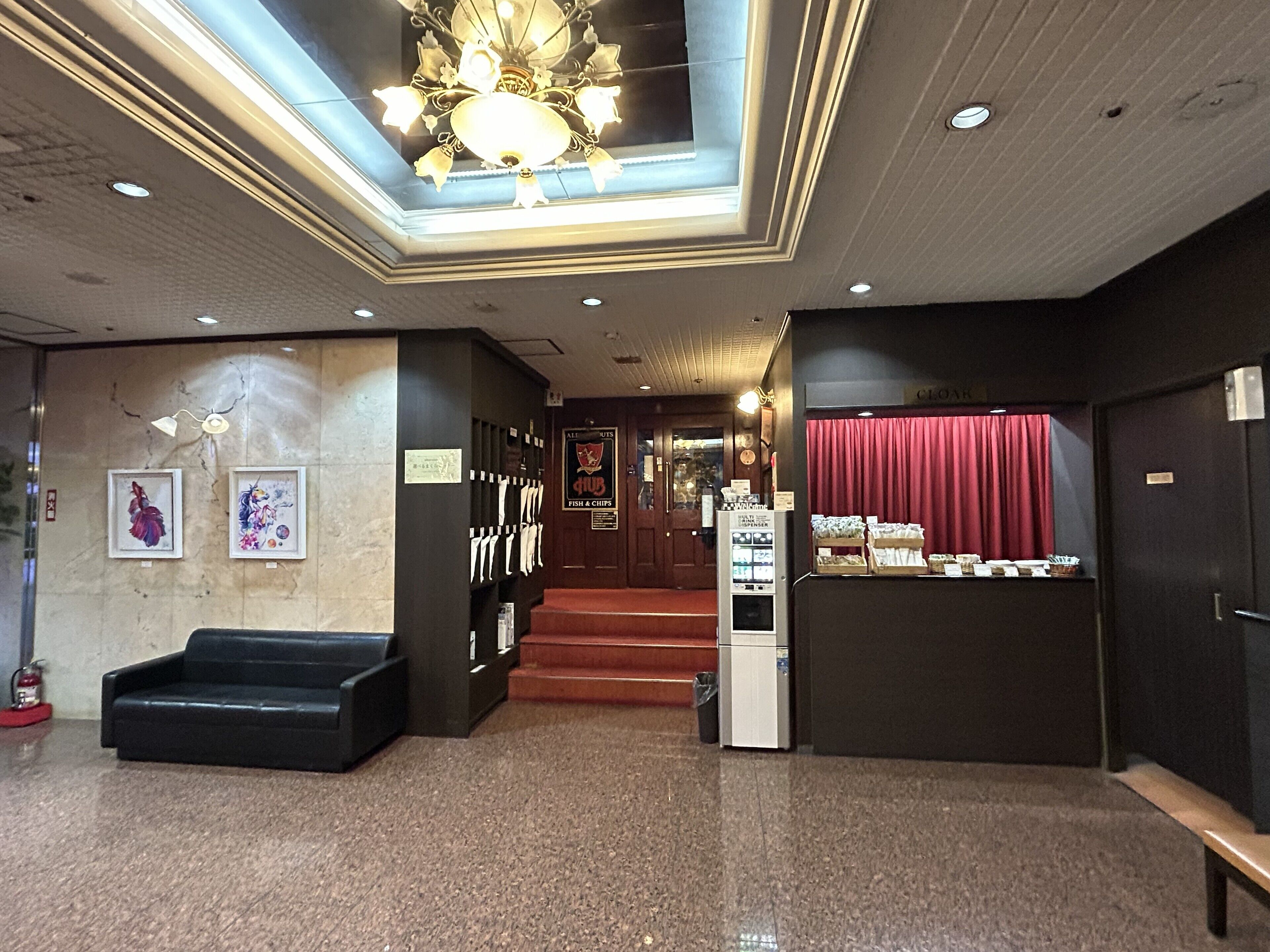 A lobby with a chandelier, framed artwork, a vending machine, and a counter with snacks.
