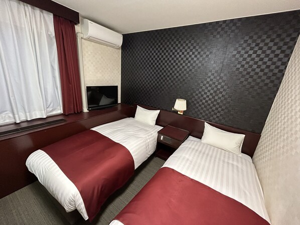 A hotel room with two beds, a TV, a lamp, and a window with curtains. - PIOLAND HOTEL (Saitama)