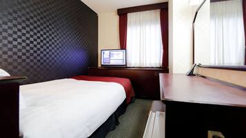 A hotel room with a bed, a desk, a television, and a window with curtains.