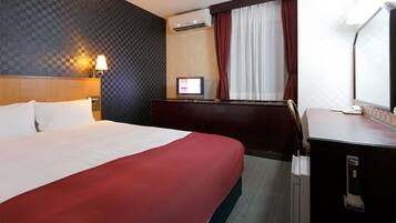 A hotel room with a bed, a desk, a TV, and a window with curtains.