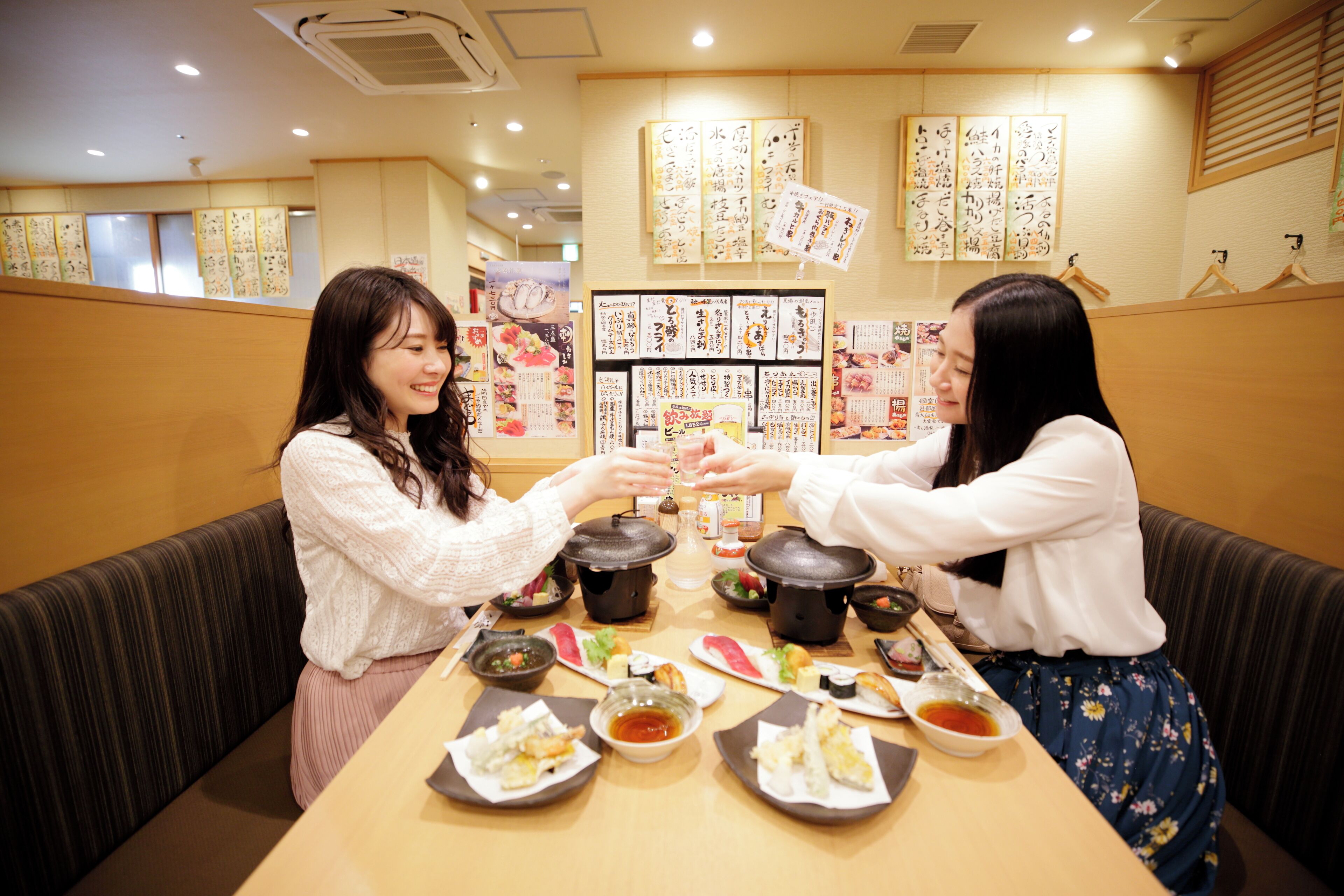 Un restaurant amb interior de fusta, taules preparades amb plats i cal·ligrafia japonesa a les parets.