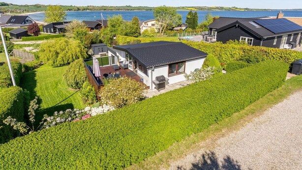 Un barrio residencial con casas, un patio con césped y un lago al fondo.