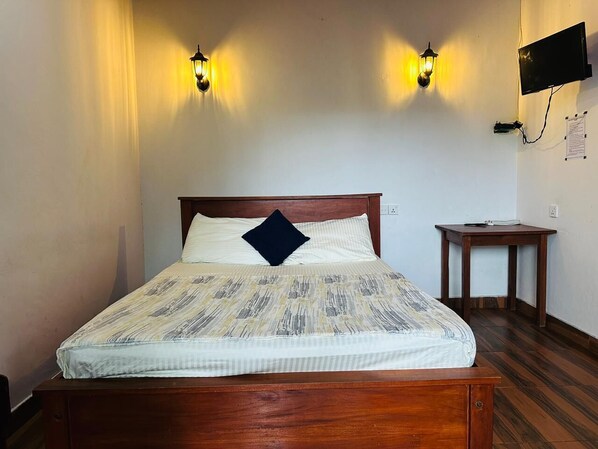 A neatly made bed with a patterned bedspread and a single pillow, flanked by two wall-mounted lamps.