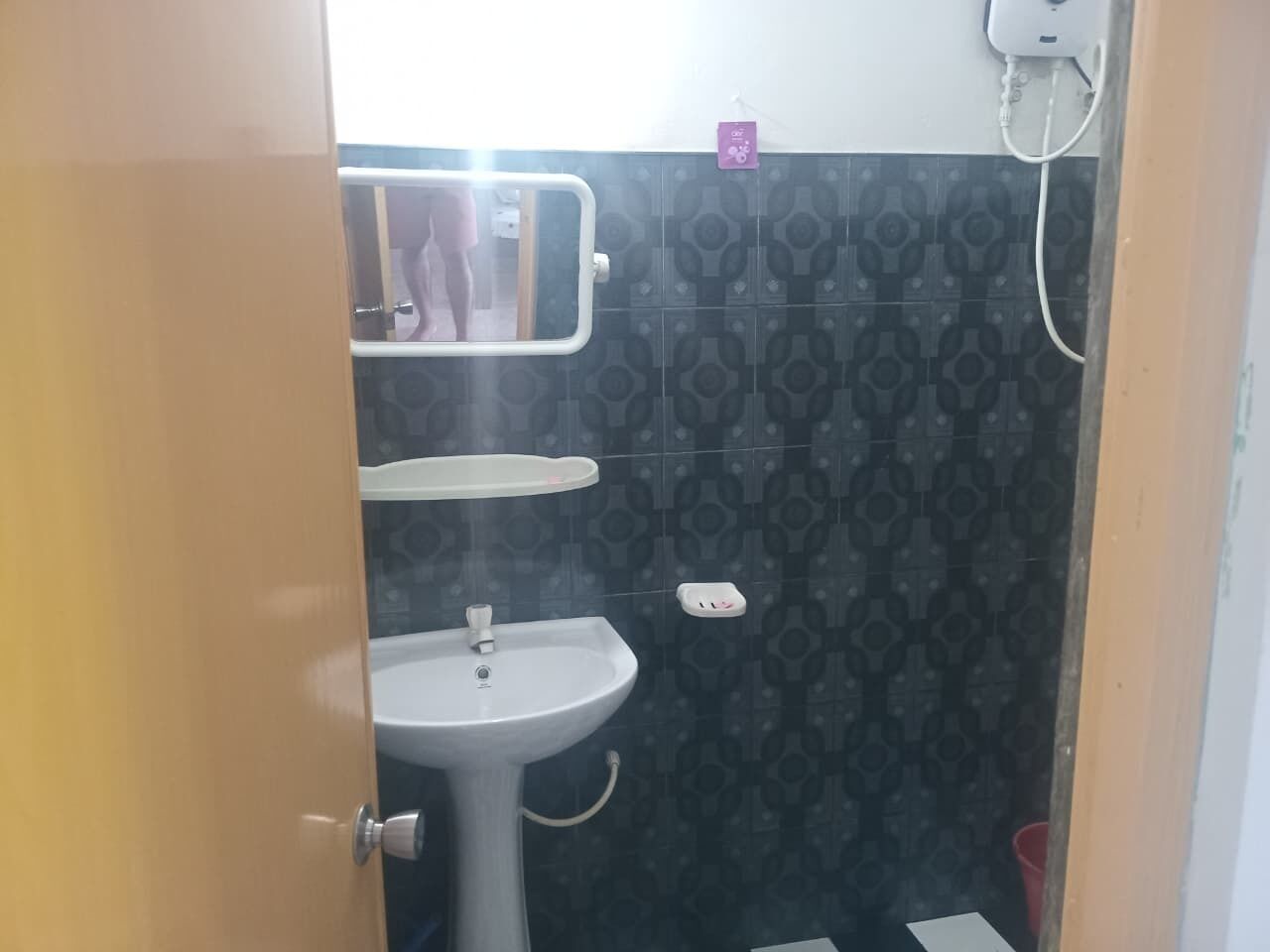 A small bathroom with a white sink, a mirror, and a towel rack.