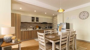 Een moderne keuken met houten kastjes, een inbouwoven en een eethoek met een houten tafel en stoelen.