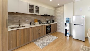 Een moderne keuken met houten kastjes, een inbouwoven, een spoelbak en een koelkast.