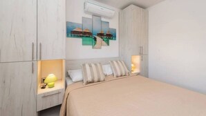 Ein Schlafzimmer mit einem Bett, einem Nachttisch mit Lampe und einer Wand-Klimaanlage.