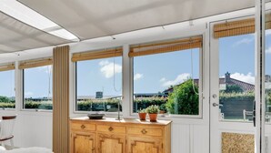 A kitchen with wooden cabinets, a white countertop, and large windows with views of greenery and buildings. - "Hjalma" - 250m to the fjord by Interhome (Farsø)