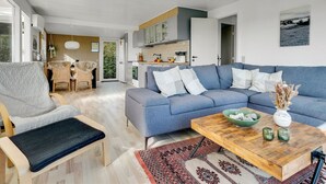 A modern living room with a blue sofa, a wooden coffee table, and a dining area with wicker chairs. - "Hjalma" - 250m to the fjord by Interhome (Farsø)