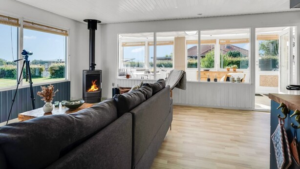 A modern living room with a sofa, a fireplace, a telescope, and large windows. - "Hjalma" - 250m to the fjord by Interhome (Farsø)