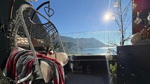 Een gezellig balkon met een hangstoel, uitzicht op zee en een heldere lucht.