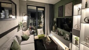 Een moderne woonkamer met een bank, fauteuil en salontafel. Er is een groot raam met uitzicht op een stadsbeeld.