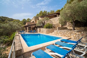 A swimming pool with blue lounge chairs, surrounded by stone walls and olive trees. - Ca Na Xilla Alcanada 8 people pool (Alcúdia)