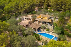 Eine Villa im mediterranen Stil mit einem Swimmingpool, umgeben von üppiger Vegetation.