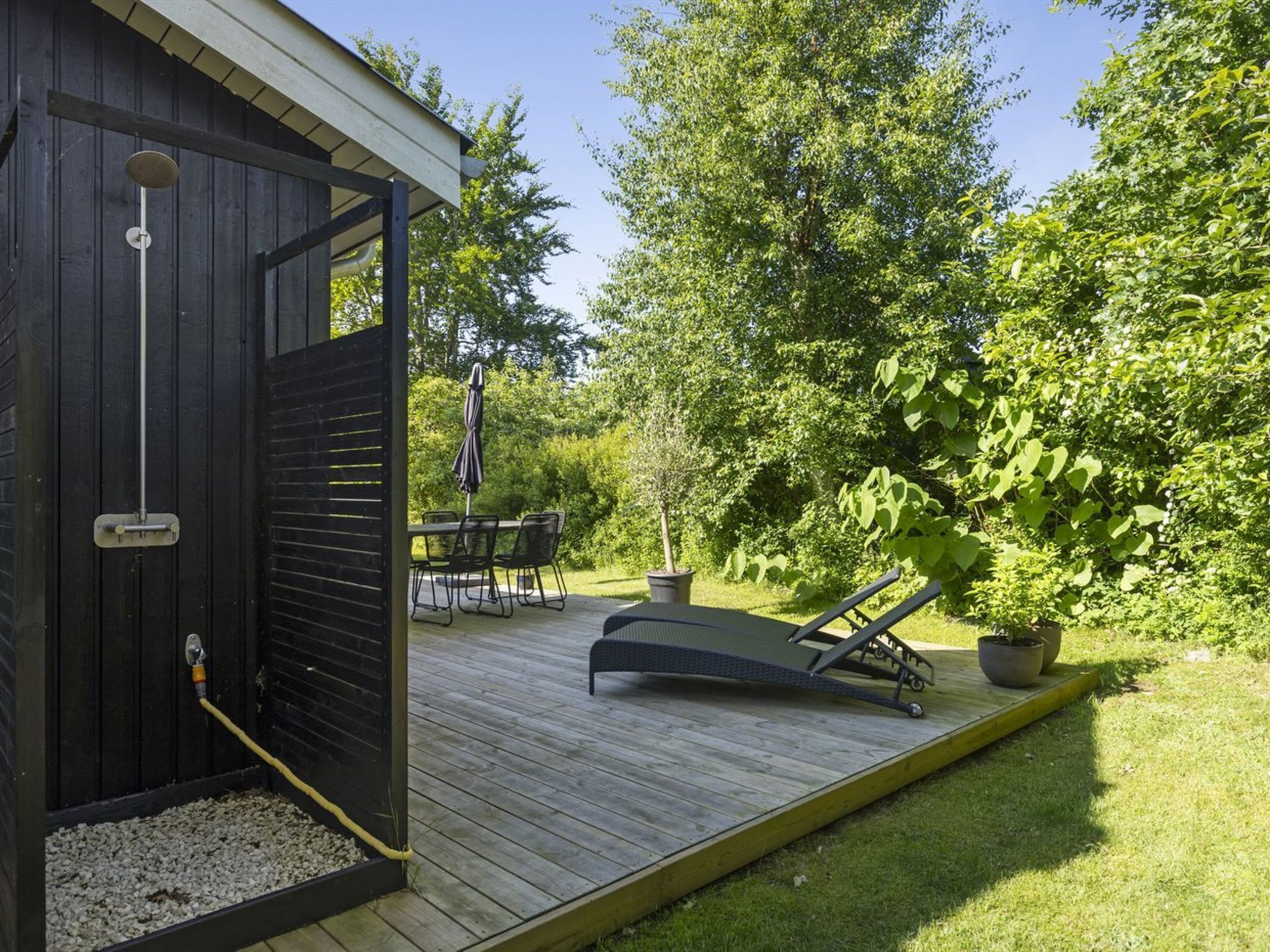 Een houten terras met een overdekte zithoek, een pooltafel en een lounge stoel.