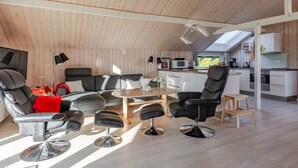 En moderne, åben planløsning med loft til kip, et køkkenområde og et siddeområde med sofabord.