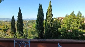 Un patio con una mesa y sillas, con vista a un paisaje de árboles y edificios.