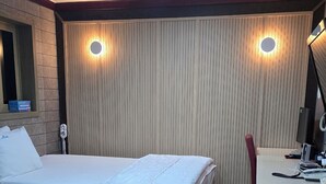 A hotel room with a bed, desk, and a wall-mounted light fixture. - Sky Motel (Gumi)
