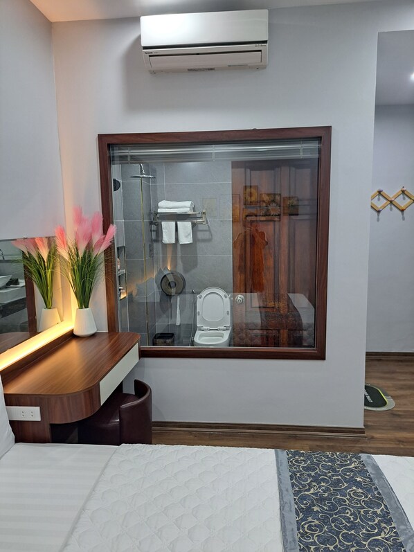 Un baño moderno con cabina de vidrio, tocador de madera y un inodoro.