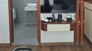 A modern bathroom with a shower, toilet, and sink. A flat-screen TV is mounted on the wall above a wooden vanity with a mirror. - Hoang Gia Luxury (Hanoi)