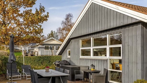En uteplats med ett bord och stolar, en grill och krukväxter.
