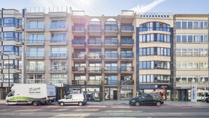 Un immeuble à plusieurs étages doté d’une architecture moderne, avec des balcons et de grandes fenêtres.