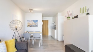 Un salon moderne comprenant un canapé, une table à manger et des chaises. Il y a également un coin cuisine avec des placards et un réfrigérateur.