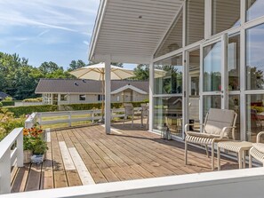 A wooden deck with outdoor furniture, a covered seating area, and a view of neighboring houses. - "Finn" - 100m from the sea by Interhome (Sydals)