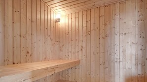 Una sauna in legno con panche e un lampadario.