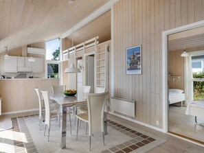 A modern kitchen with white cabinets, a dining table with chairs, and a view of the outdoors. - "Finn" - 100m from the sea by Interhome (Sydals)
