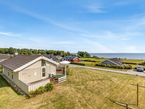 A residential area with houses, a grassy lawn, and a body of water in the background. - "Finn" - 100m from the sea by Interhome (Sydals)