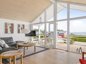 A spacious living area with a large glass door leading to an outdoor deck, a comfortable sofa, a coffee table, and artwork on the walls. - "Finn" - 100m from the sea by Interhome (Sydals)