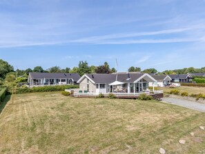 A row of modern, single-story houses with large windows and attached porches, surrounded by well-maintained lawns and trees. - "Finn" - 100m from the sea by Interhome (Sydals)