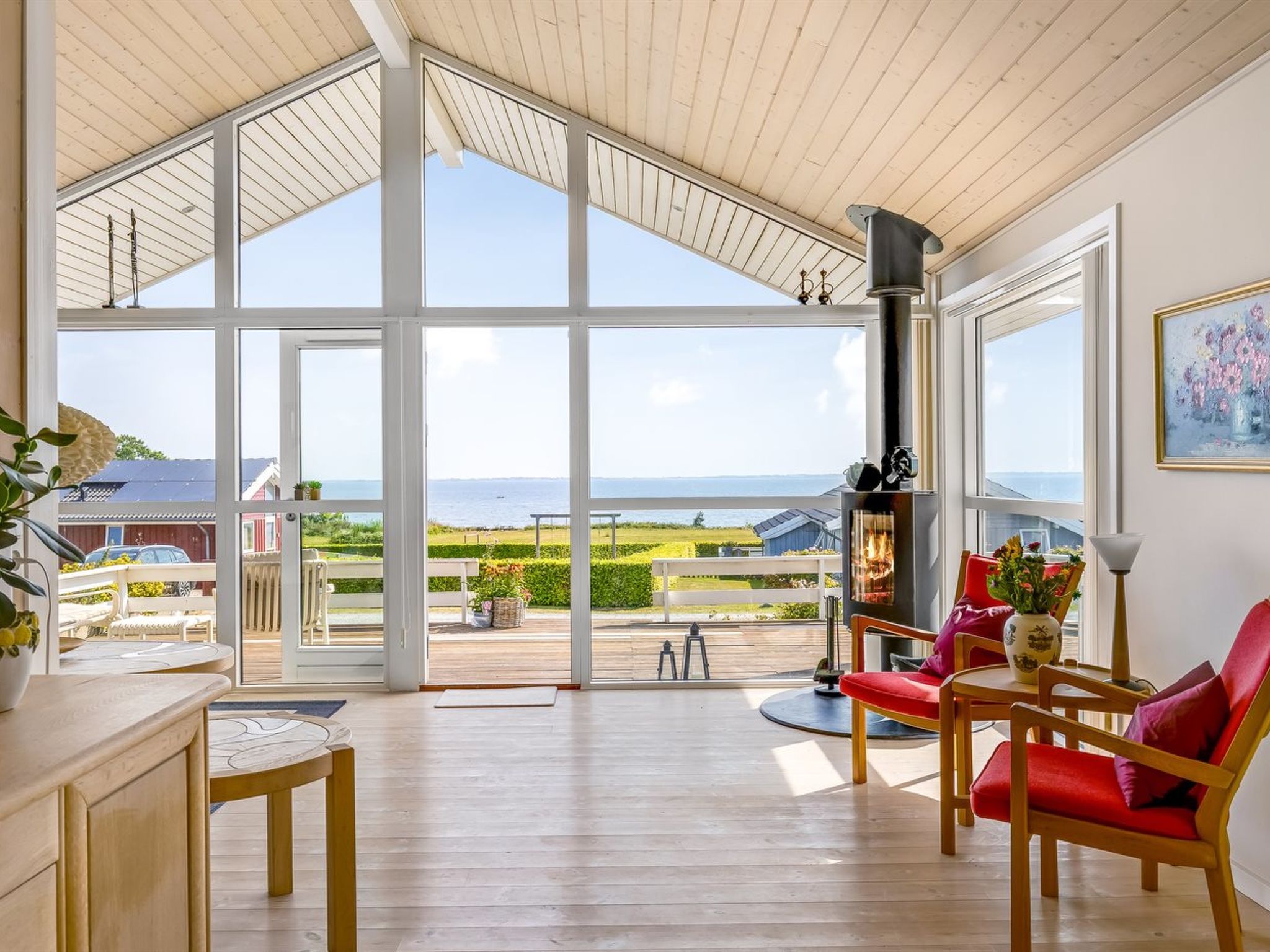 A spacious room with a large glass door leading to an outdoor area, a fireplace, and a view of the sea.