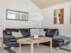 A modern living room with a leather sofa, a wooden coffee table, a white pendant light, and a framed artwork on the wall. - "Finn" - 100m from the sea by Interhome (Sydals)