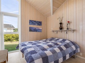 A bedroom with a large bed, wooden walls, a window, and two wall-mounted pictures. - "Finn" - 100m from the sea by Interhome (Sydals)