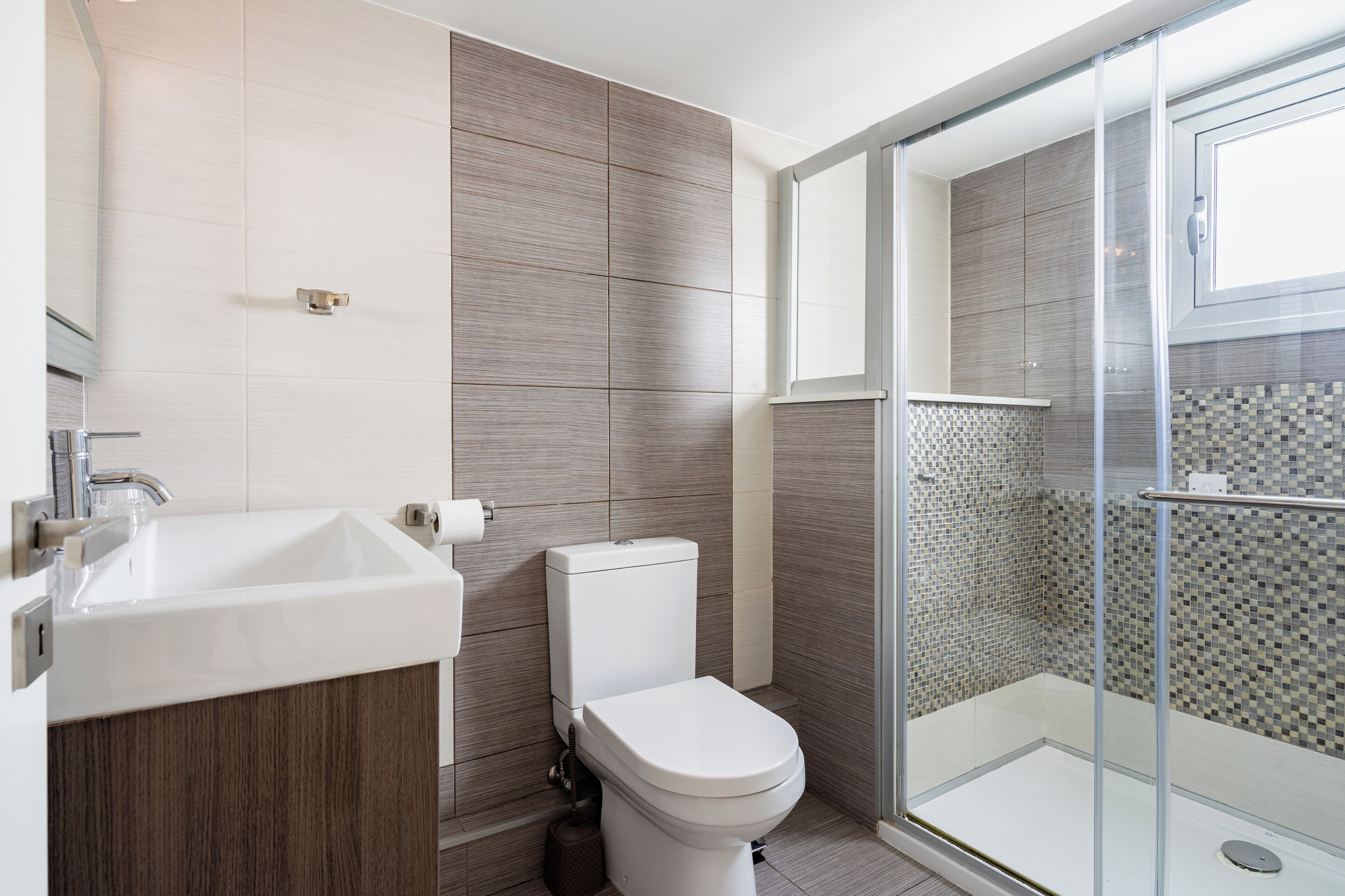 A modern bathroom with a sink, toilet, and glass-enclosed shower.