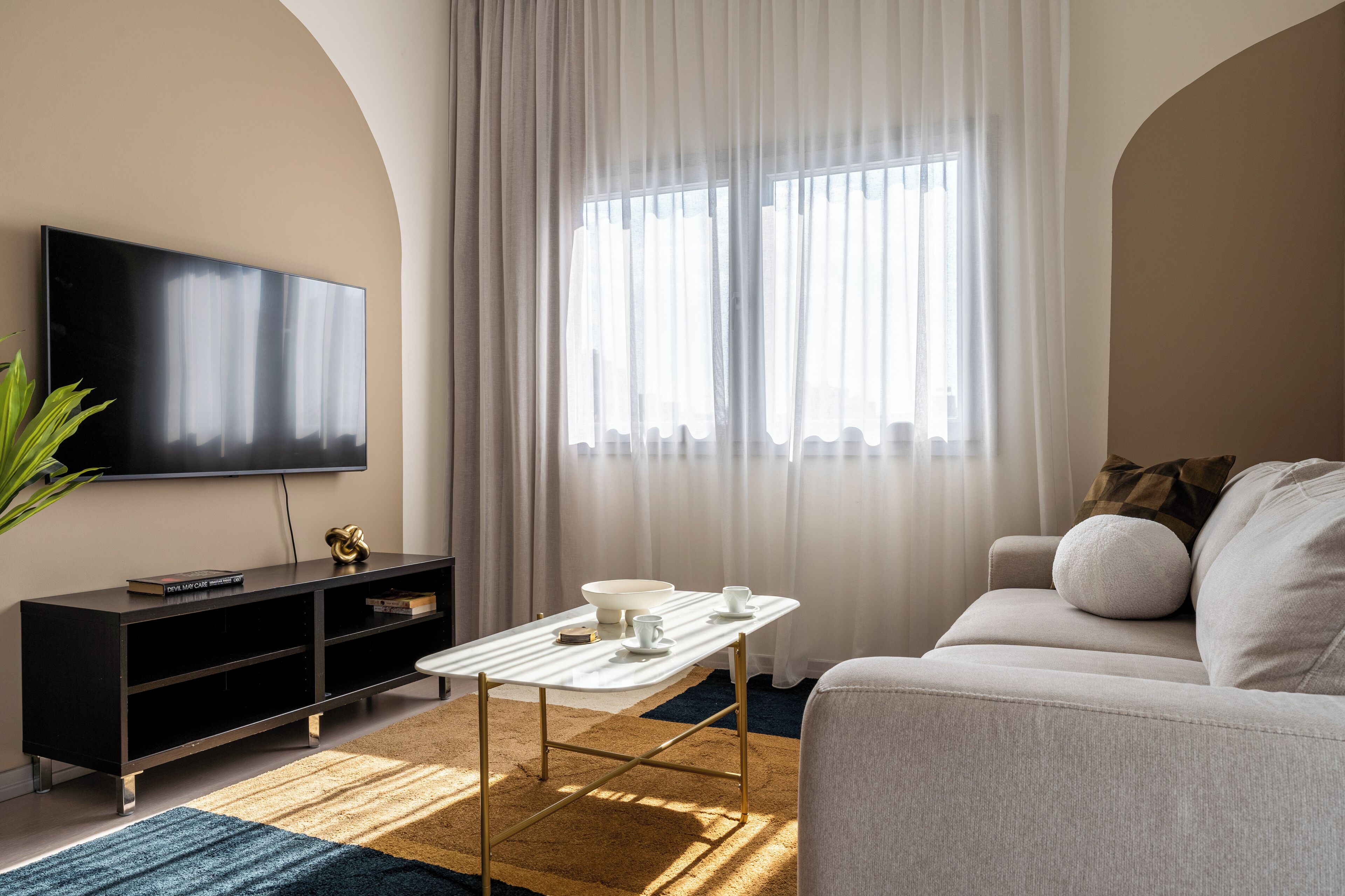 Een moderne woonkamer met een flatscreen televisie, een witte salontafel en een bank.