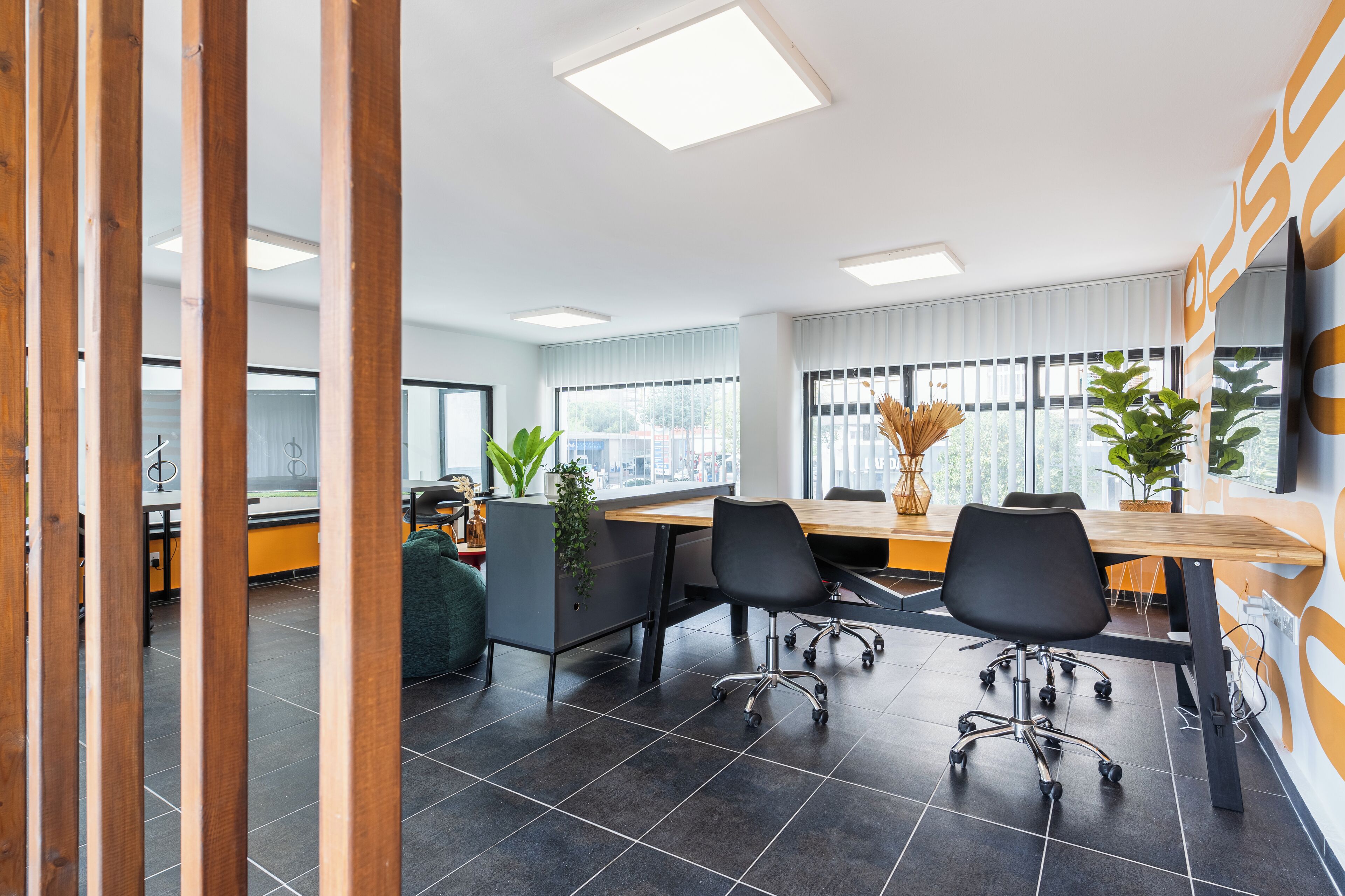 A modern office space with a long table, several chairs, and potted plants.