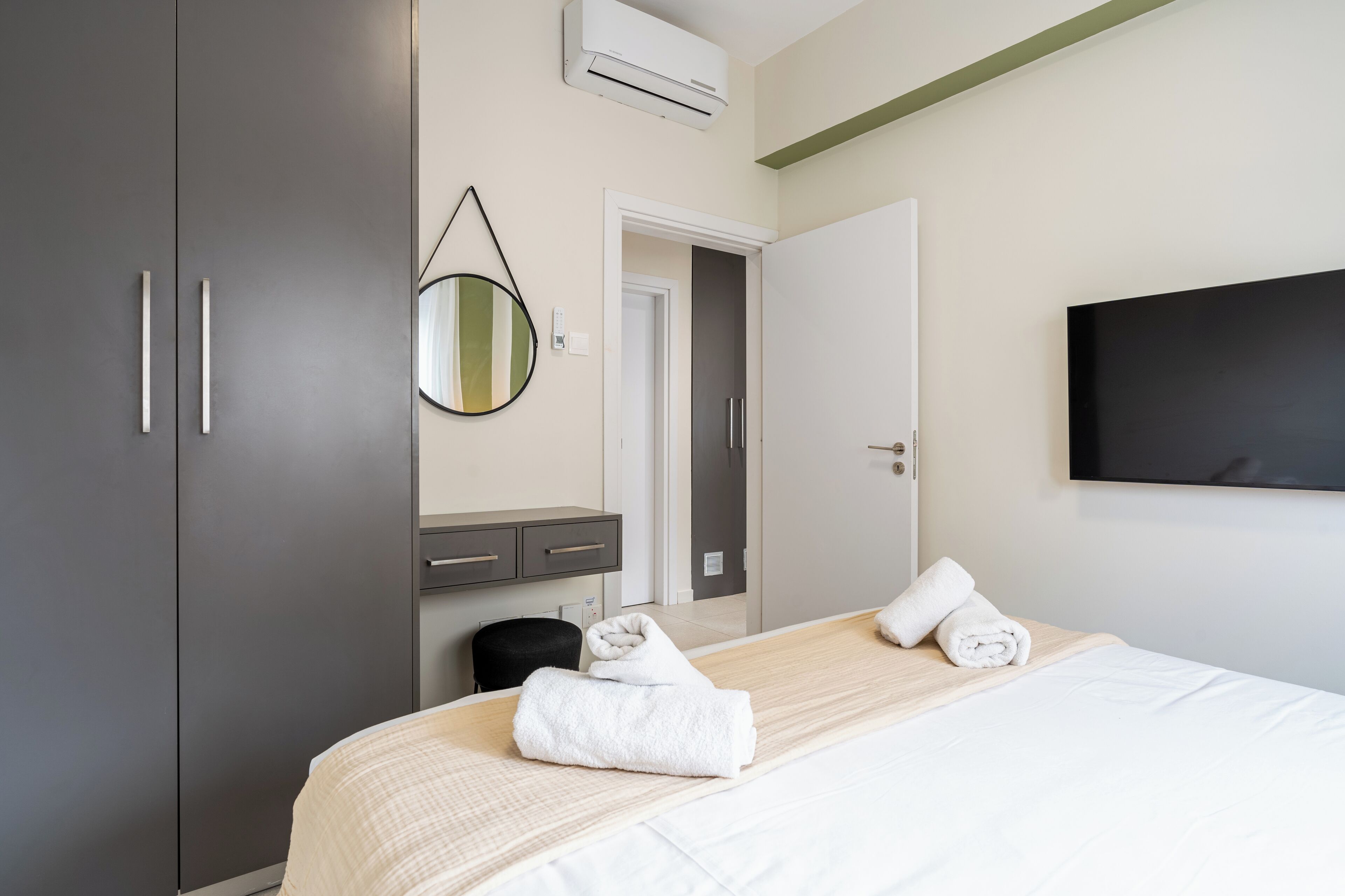 Ein modernes Hotelzimmer mit einem großen Bett, einem Kleiderschrank, einem Spiegel, einem Flachbildfernseher und einem kleinen Schreibtisch.