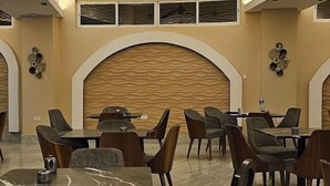 Un grand espace dédié à la salle à manger, avec plusieurs tables et chaises, un ventilateur de plafond et un décor mural texturé.