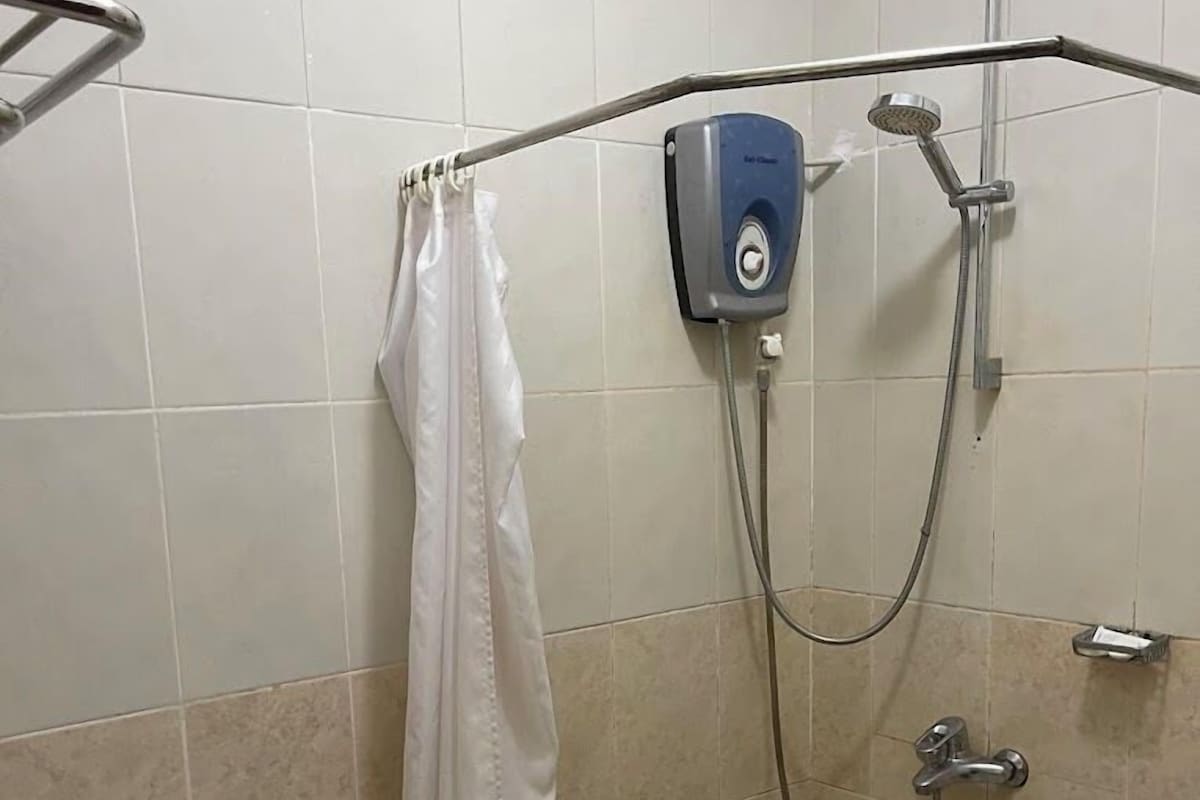 A small, tiled bathroom with a shower, toilet, and a towel rack.
