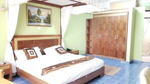 Une chambre avec un grand lit, une armoire, un bureau et un tableau au mur.