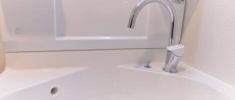 A white bathroom sink with a chrome faucet and a single drain.