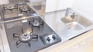 A kitchen with two gas stoves, a stainless steel sink, and a white countertop. - Zenith Nishinakanobu (Tokyo)
