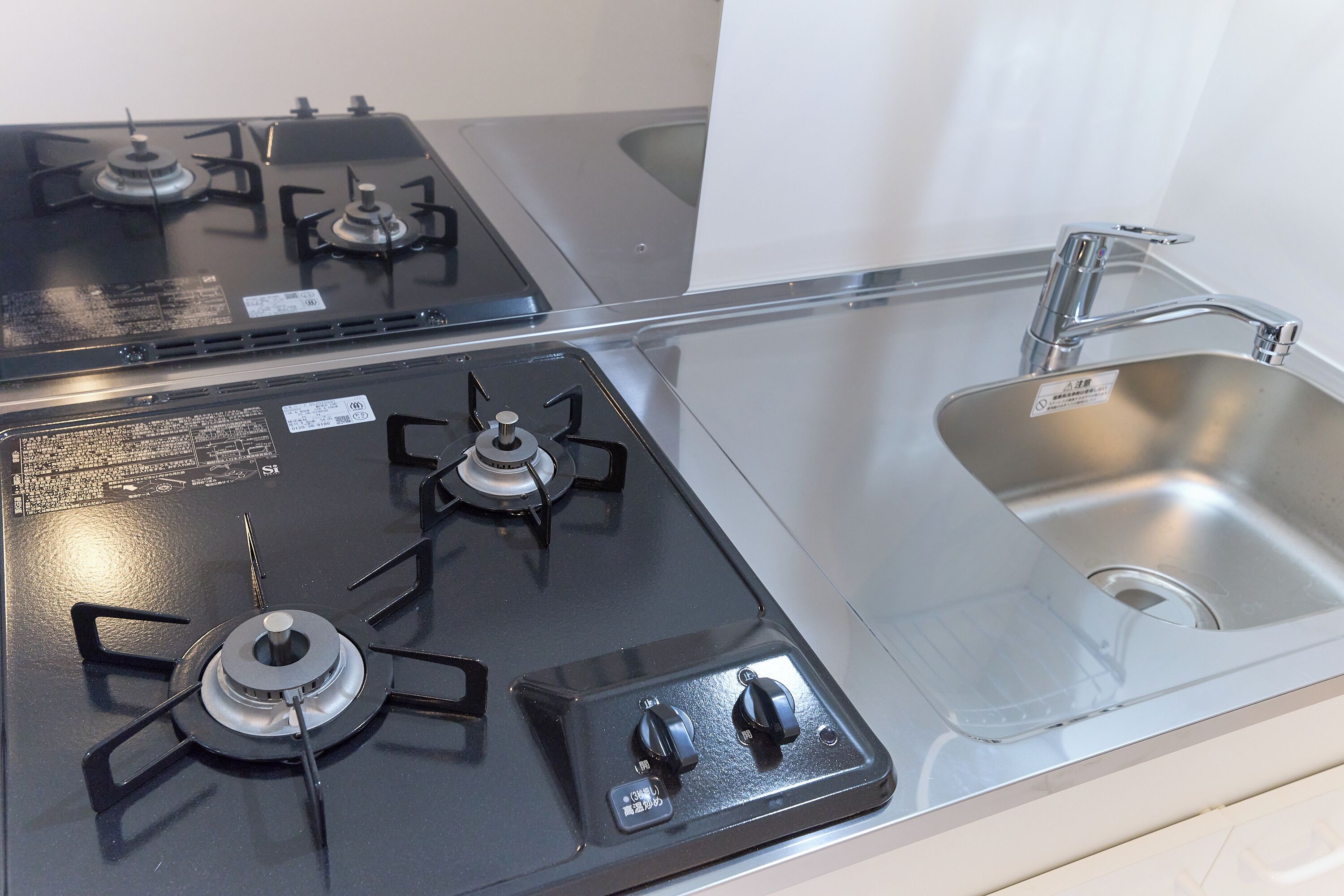 A kitchen with a gas stove, a sink, and a stainless steel countertop.