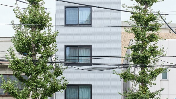 A multi-story building with a modern design, featuring a series of windows and air conditioning units on the ground floor. - Zenith Nishinakanobu (Tokyo)
